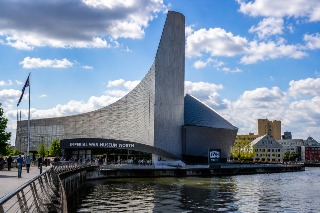 Imperial War Museum North in Manchester UK beside the waterfront with modern architecture, visitors, and blue sky